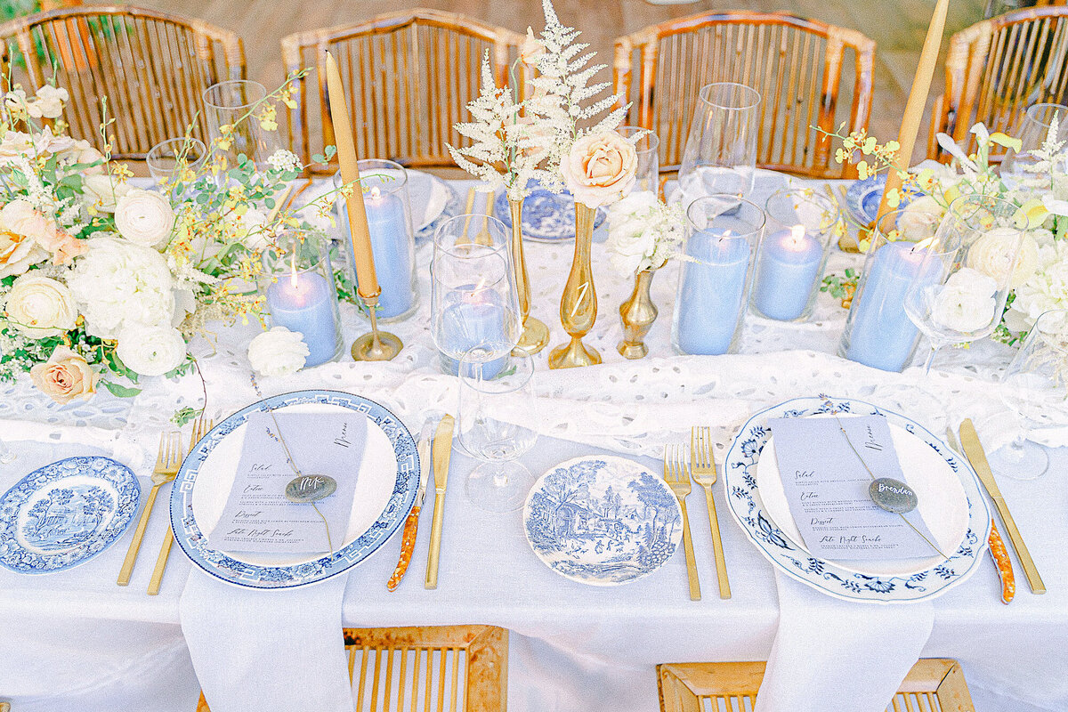 Pale blue and white china with blue and gold candle centerpieces at an intimate tented estate wedding reception