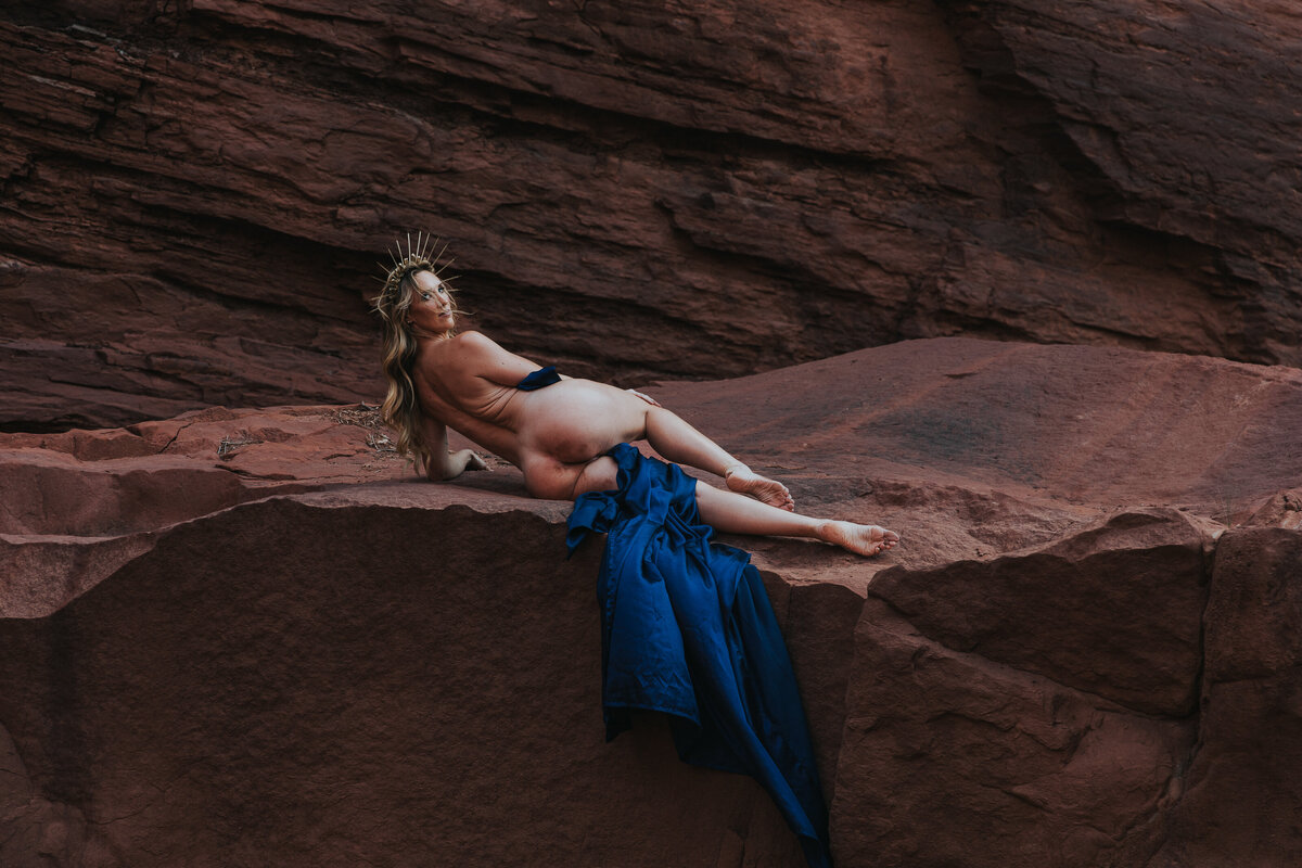 woman laying on a boulder using a sheet to cover