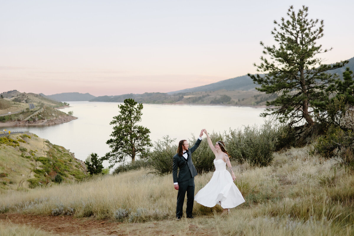 groom twirls his bride under the golden light at Horsetooth Reservoir, capturing a playful moment of celebration after their elopement in Fort Collins.