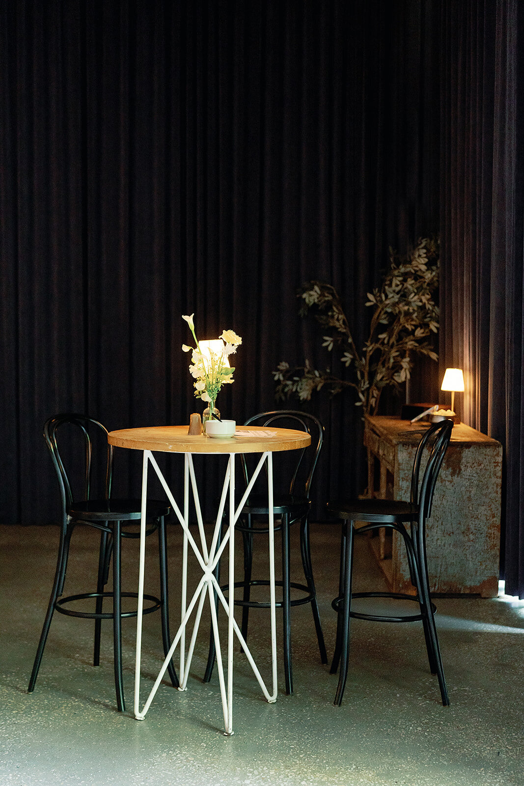 A black hightop table with black chairs in the reception room at the South Congress hotel
