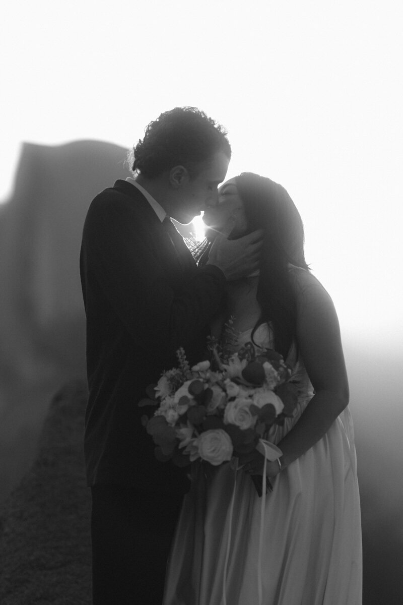 Glacier Point Wedding: Black and white of a couple kissing with sun rays between them