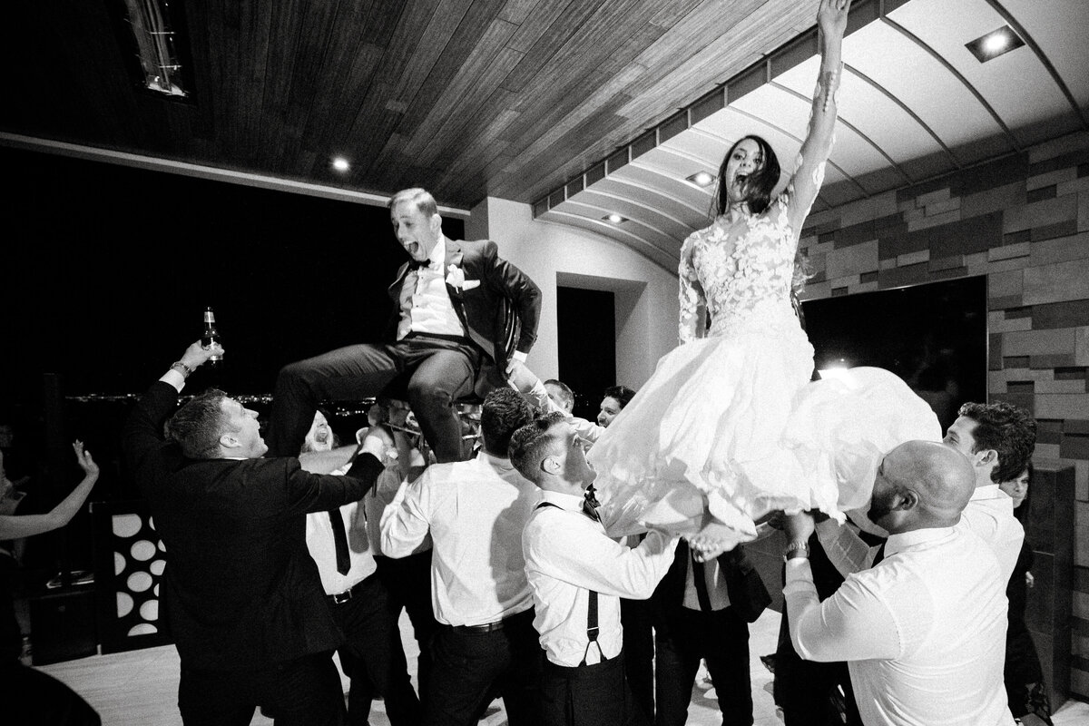 Bride and groom are lifted in the air during their wedding reception