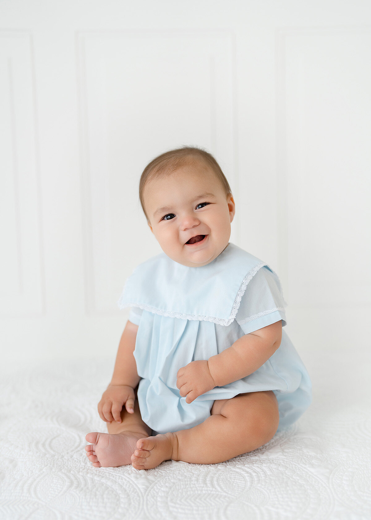smiling baby boy in a blue grandmillenial style outfit photographed in sea island photo studio