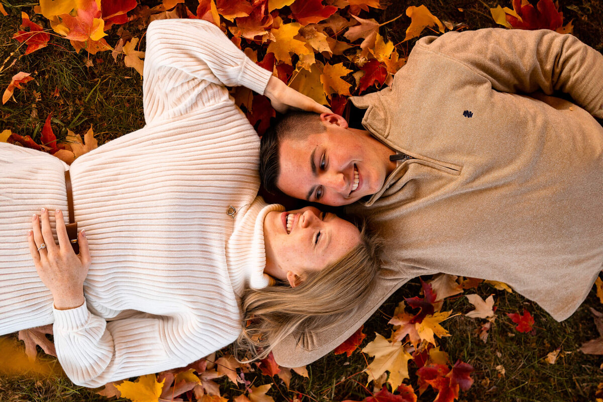 Pittsburgh engagement photography of a of a couple smiling and holding each other in a pile of autumn leaves