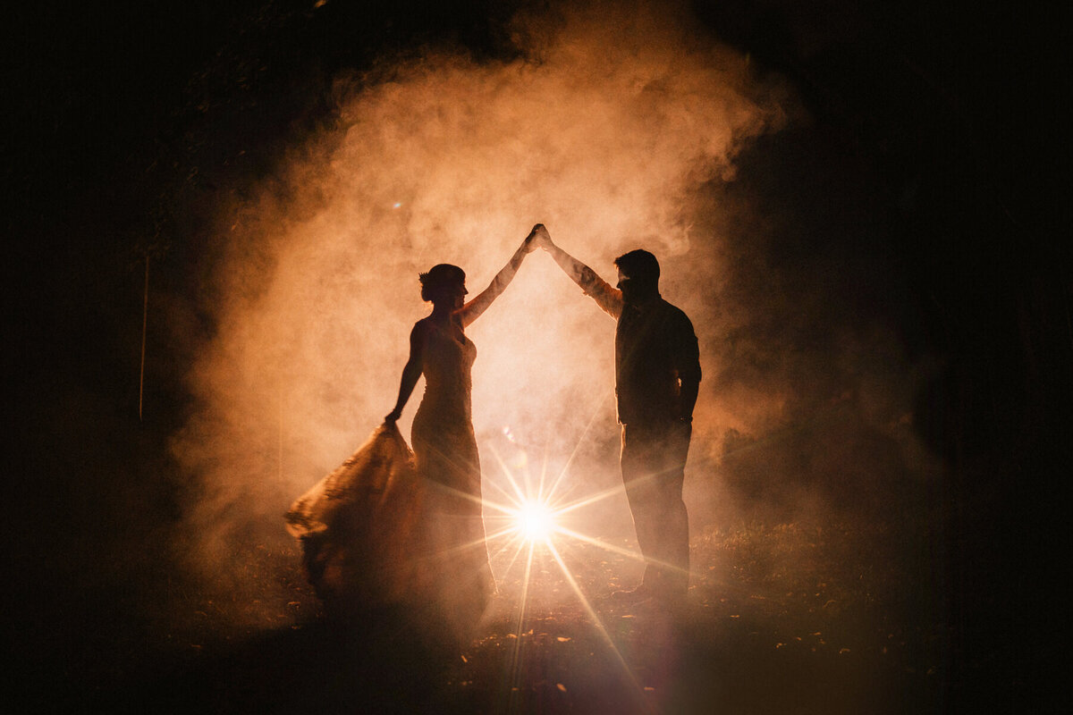 Silhouetted bride and groom dancing under a spotlight with smoke and stars at Broadfield Court, a luxury wedding venue in Herefordshire.