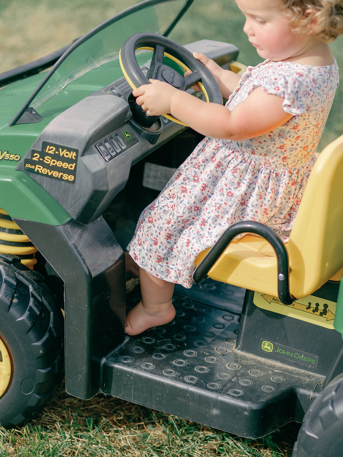 Toddler girl riding on toy john deer