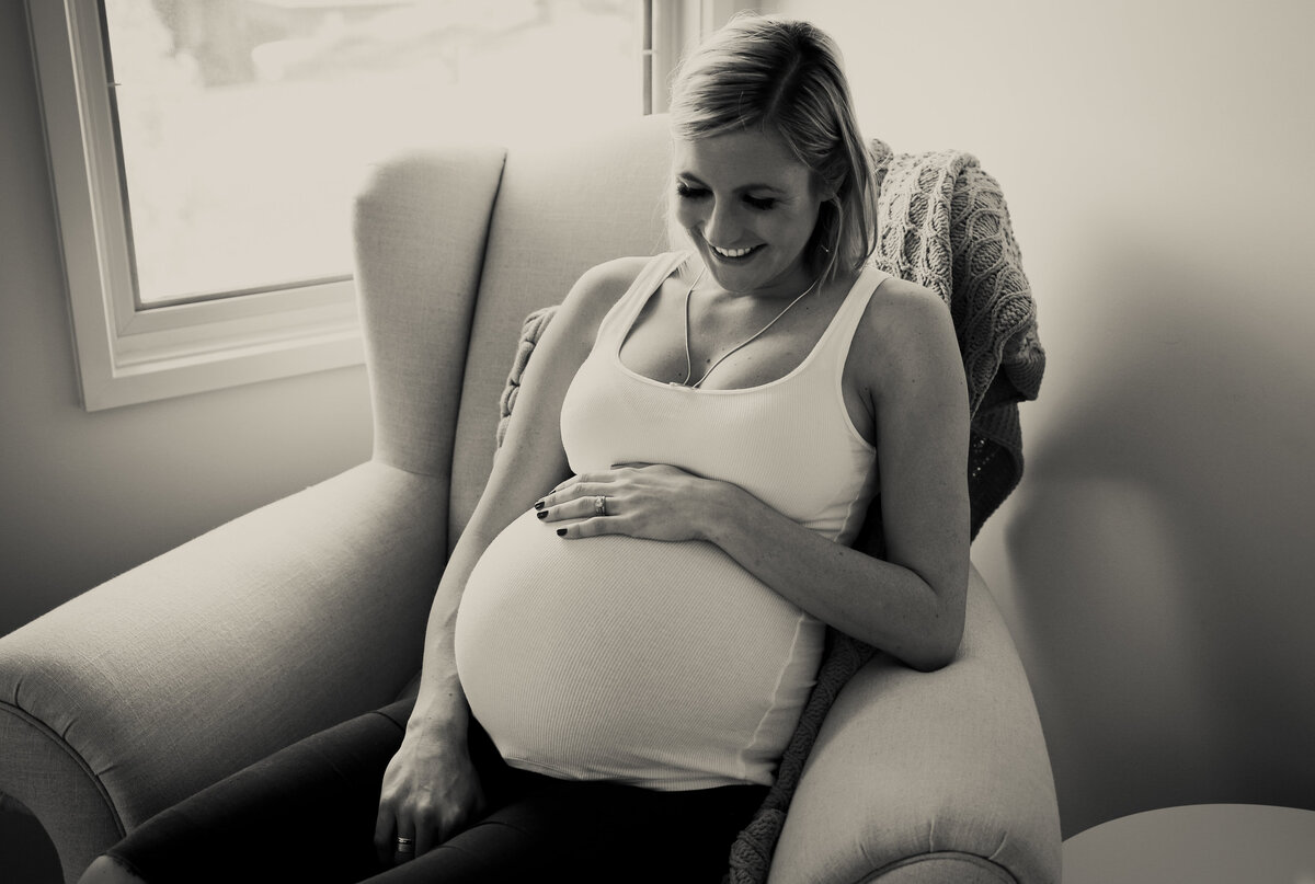 Pregnant woman smiling in armchair,  maternity photography Melbourne by And So I Don't Forget Photography