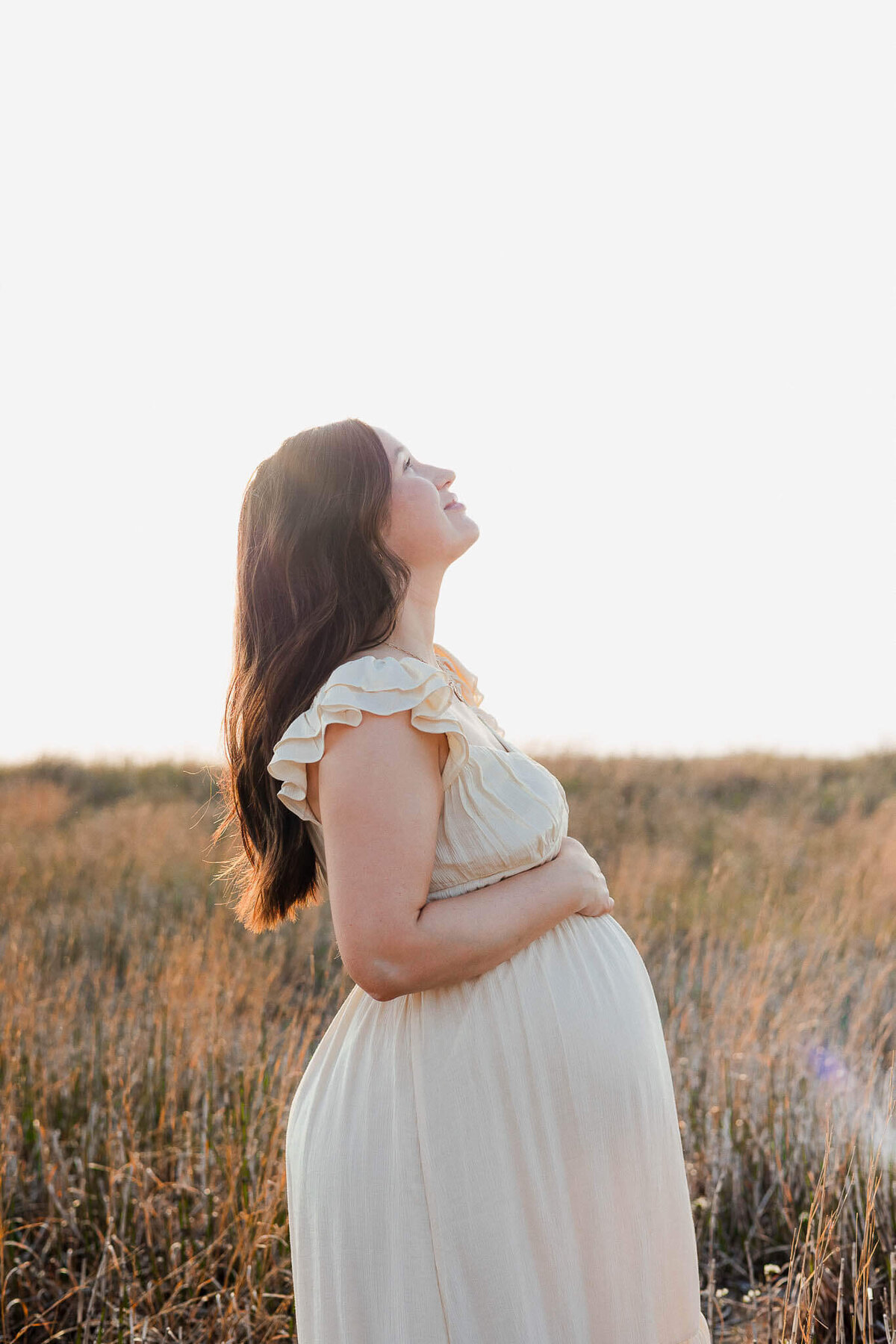 A maternity portrait at sunset capture a glowing moment at a Cleveland beach during a lifestyle photography session.