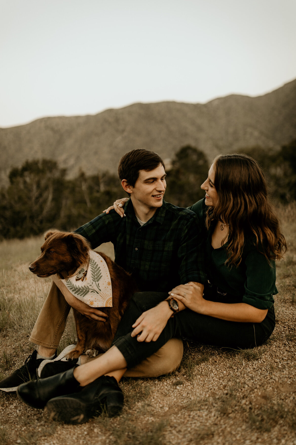 engaged couple sitting together with their dog  in the New Mexico desert