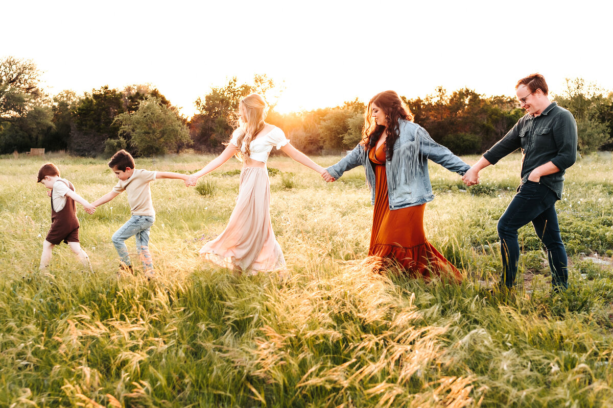 family holding hands walking through a field