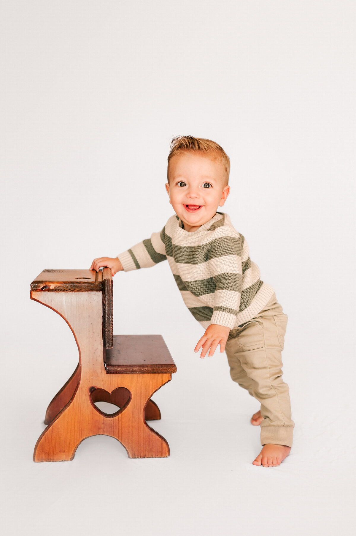 toddler boy standing up on stool in Springfield MO photography studio specialized for kids