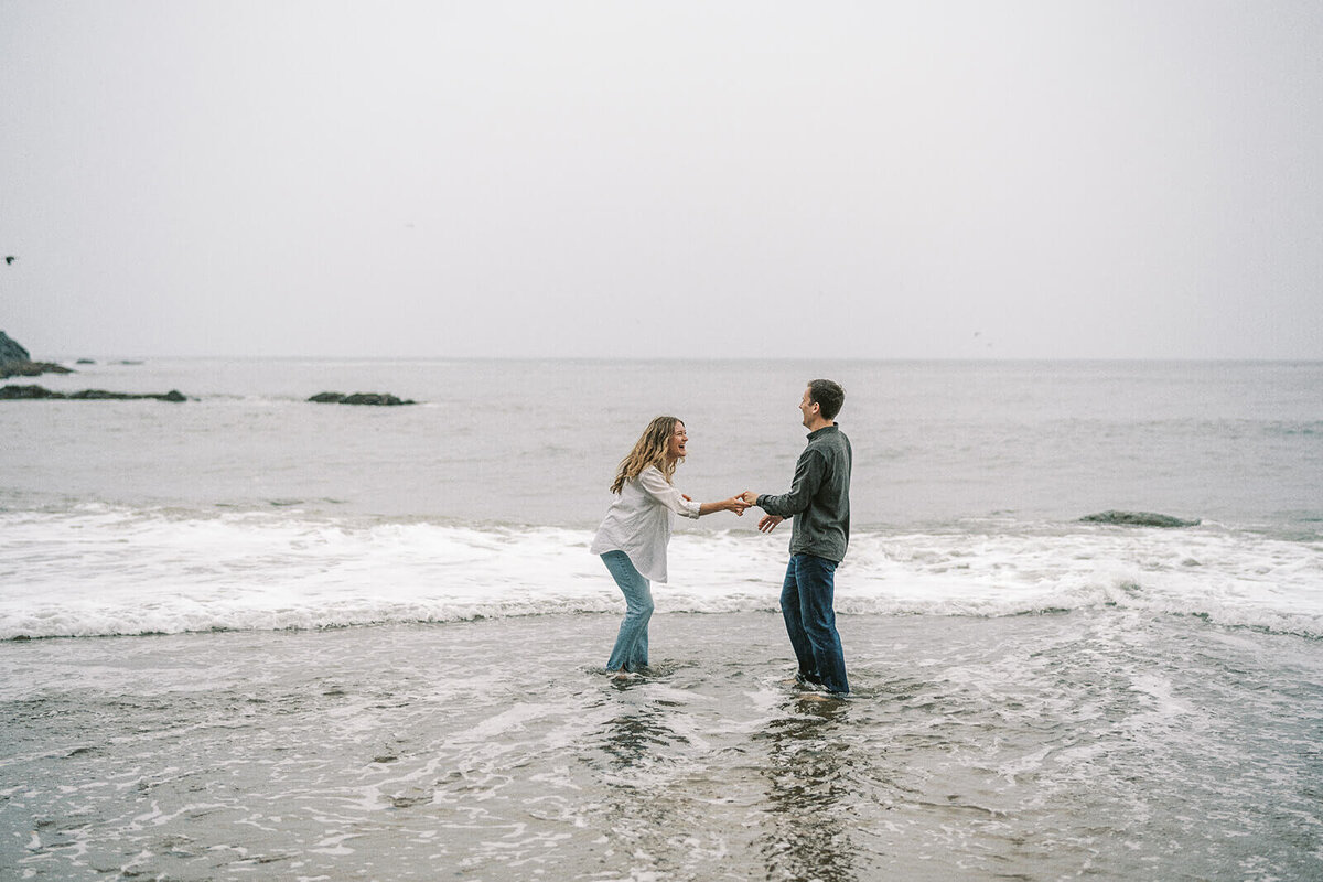 A couple laughing while playing in the waves.