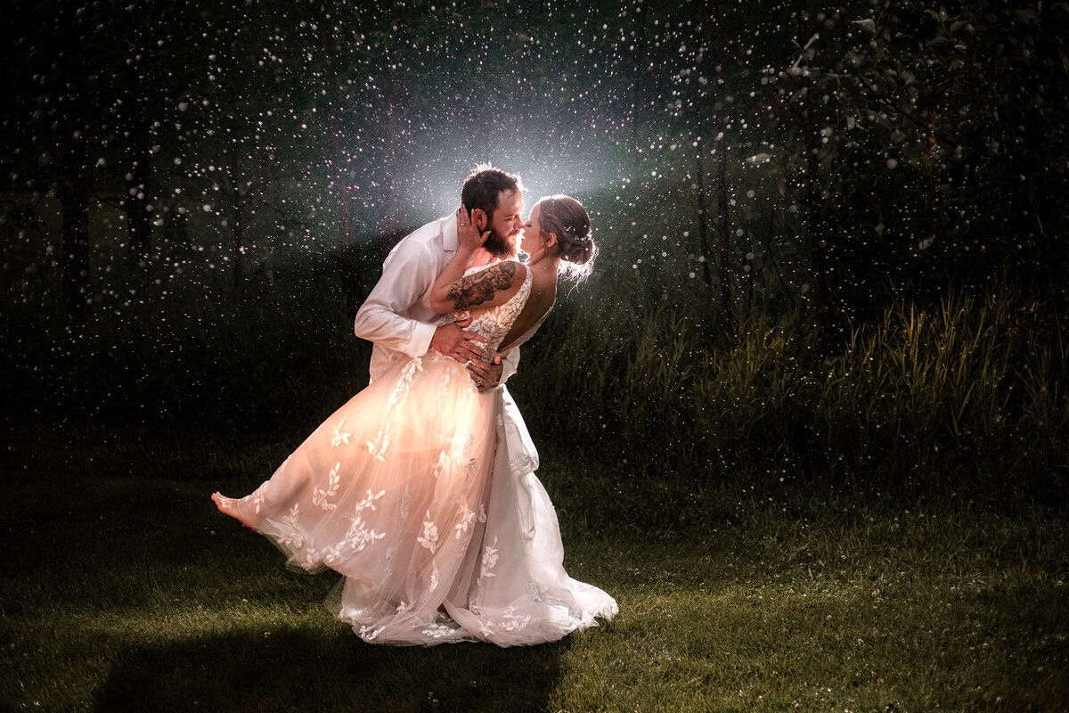 Groom dipping his bride in the pouring rain