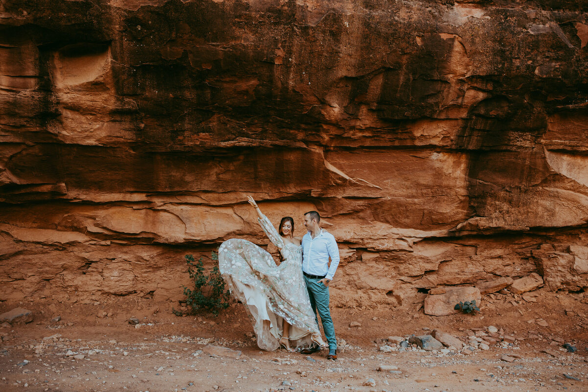 couples stands in front of red rock wall in Sedona Arizona