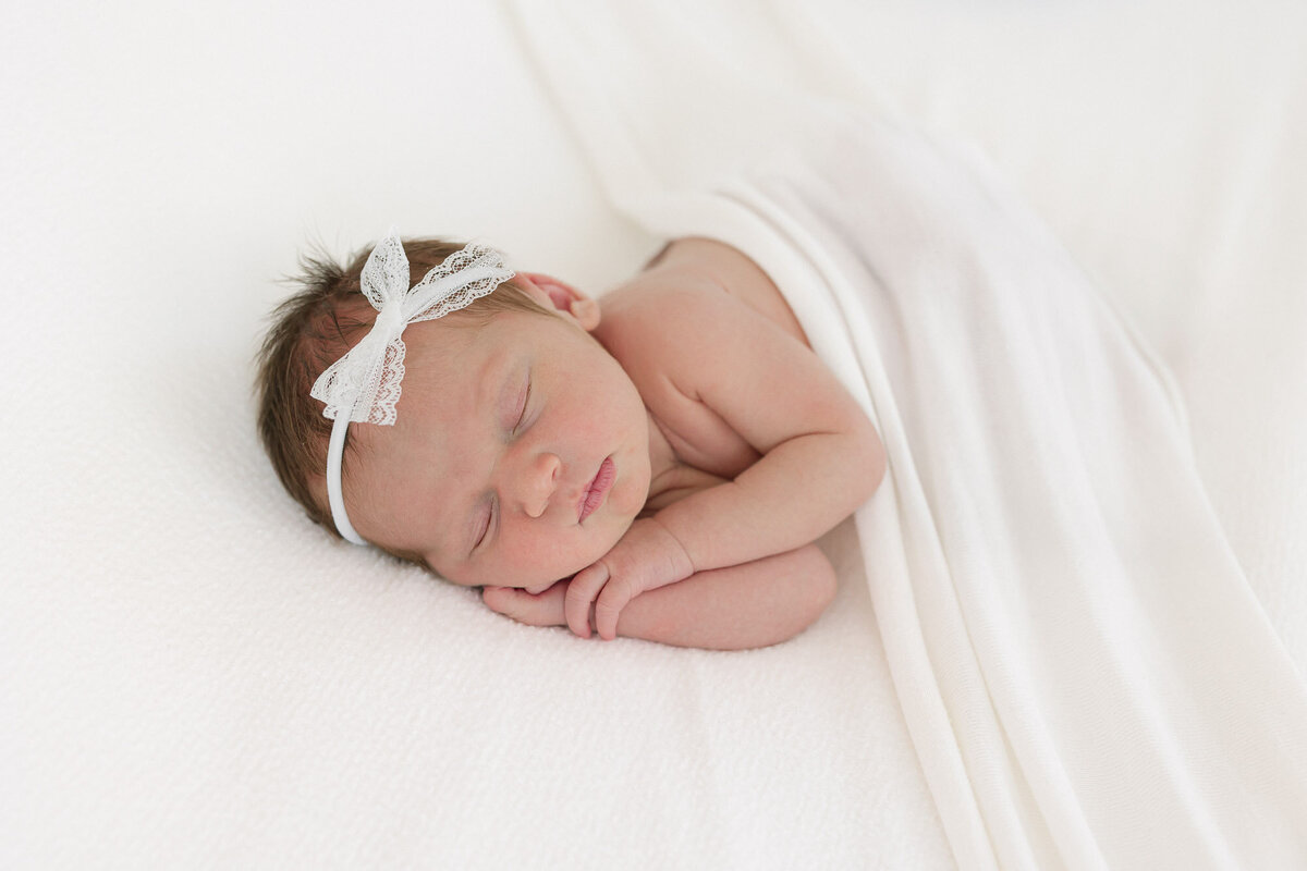 Newborn baby girl lying on her side with her hands under her cheek while she sleeps during her louisville newborn photography session