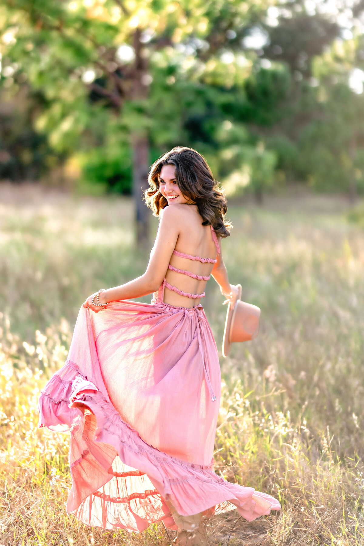 Senior girl twirling looking over shoulder with soft smile in Windermere field