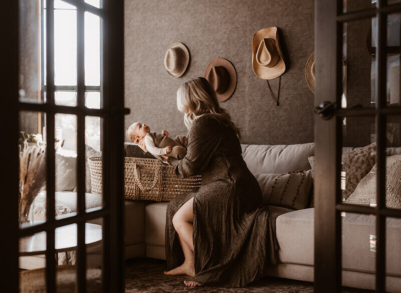 Peeking through two black doors, mom places baby in Moses basket