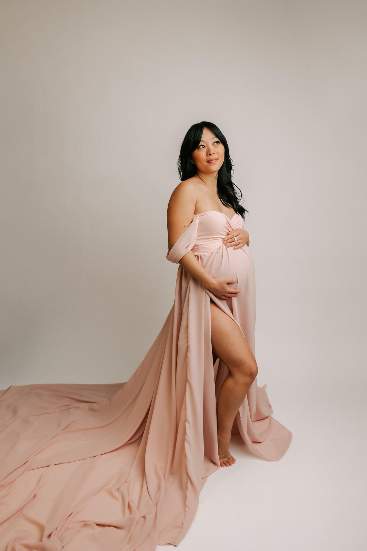 smiling mom holding belly wearing couture pink dress expecting baby girl this sping