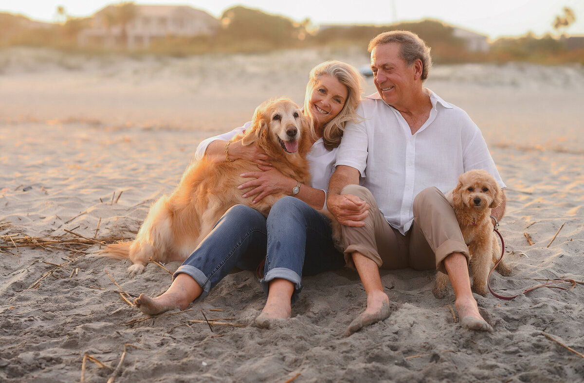 Couple embraces their dogs during Family Photoshoot on Isle of Palms beach. 