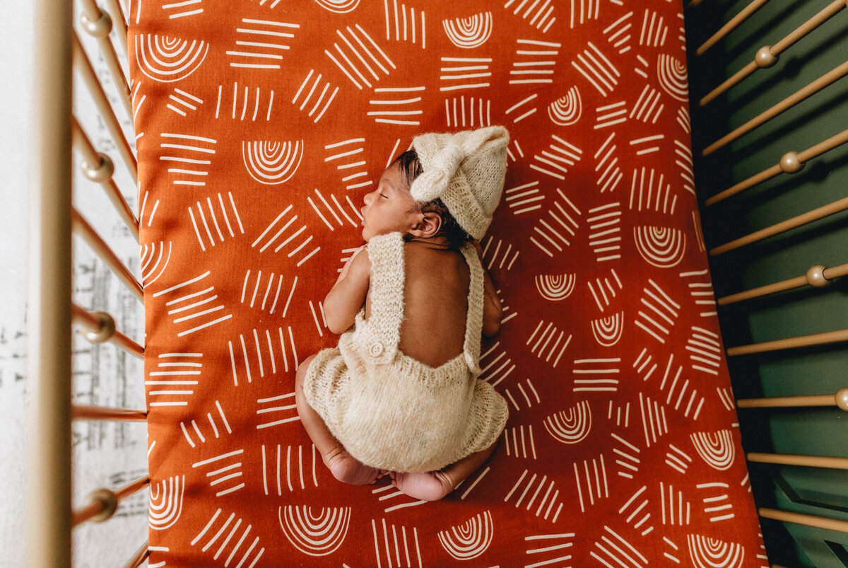 Infant photography session with newborn sleeping in a crib.