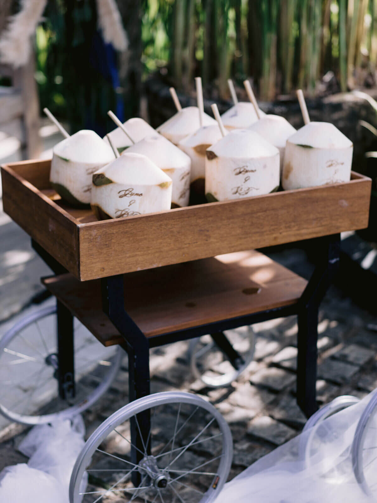 Coconuts ready to drink with a straw, are on a wooden display cart for a wedding in Khayangan Estate, Indonesia. Image by Jenny Fu Studio