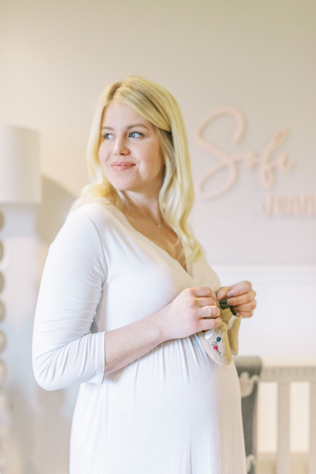 spokane wa maternity photography of mom holding baby shoes in nursery