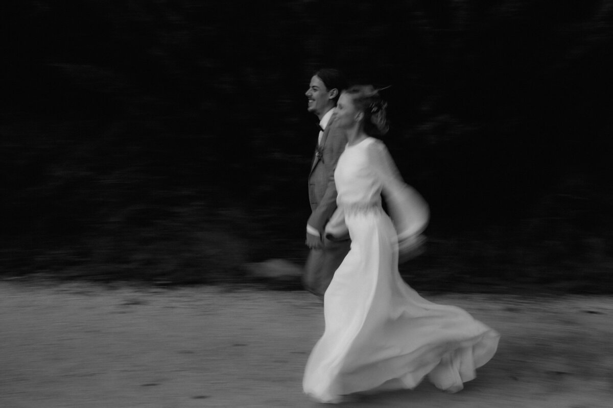 The wedding couple run through the sand holding hands.