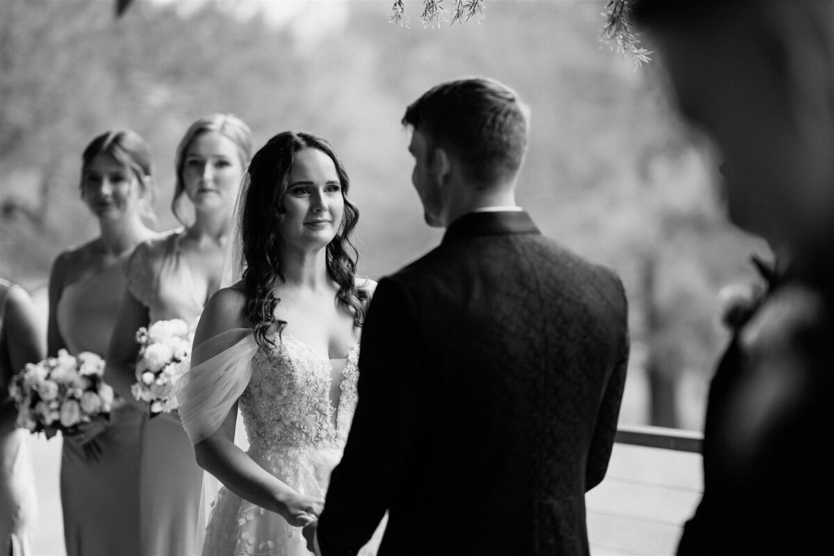 A black-and-white photograph capturing the bride's emotional reaction upon seeing her groom.