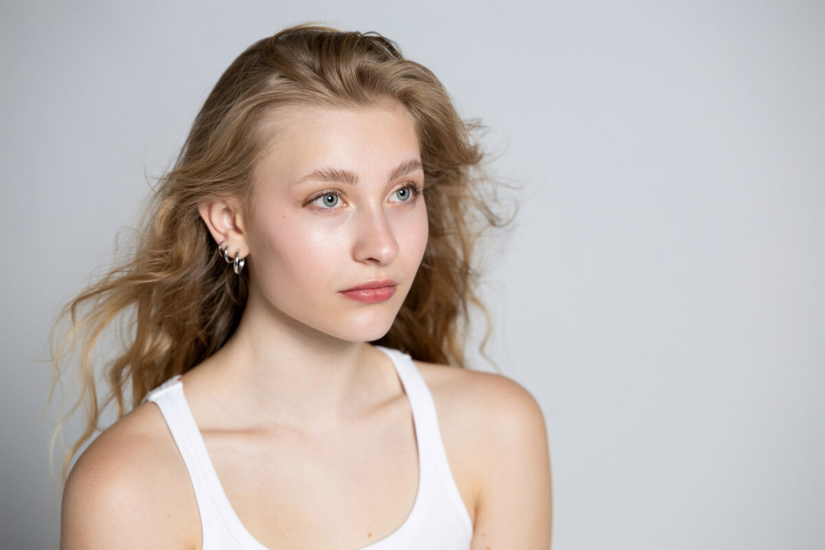 Senior girl posing in white tank top against a white background in Utah studio.