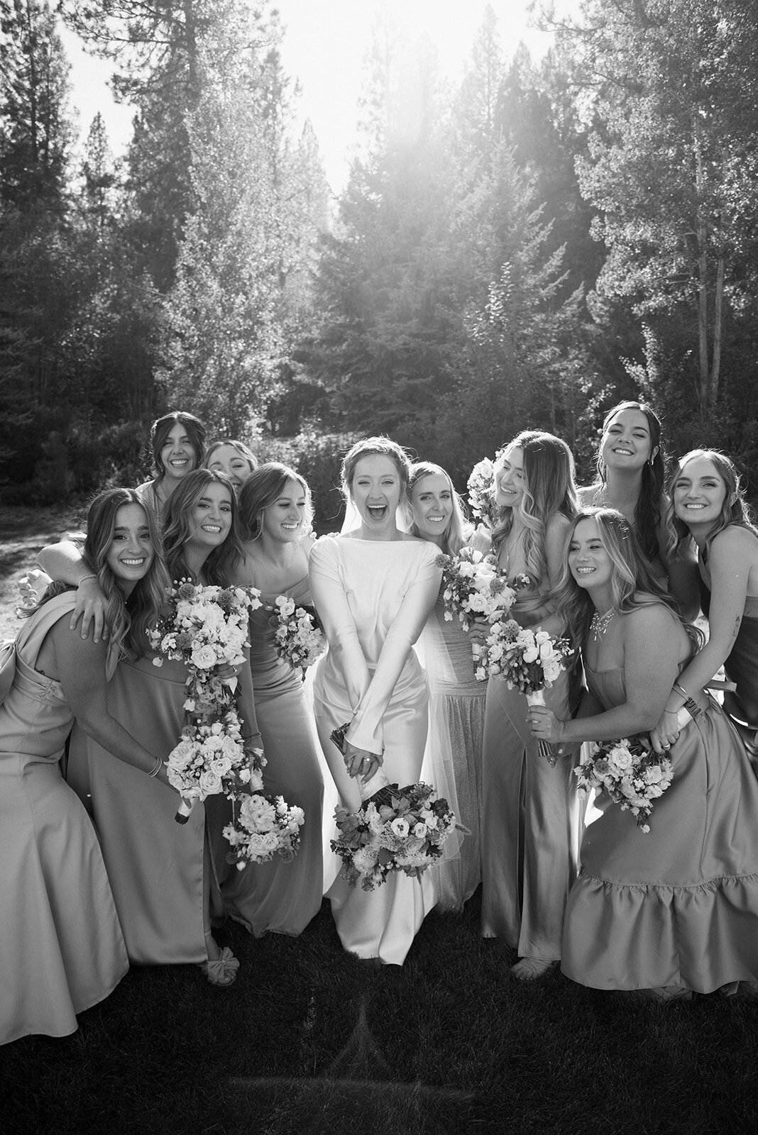 A Bride and her bridal party hold their bouquets of wedding flowers and smile.