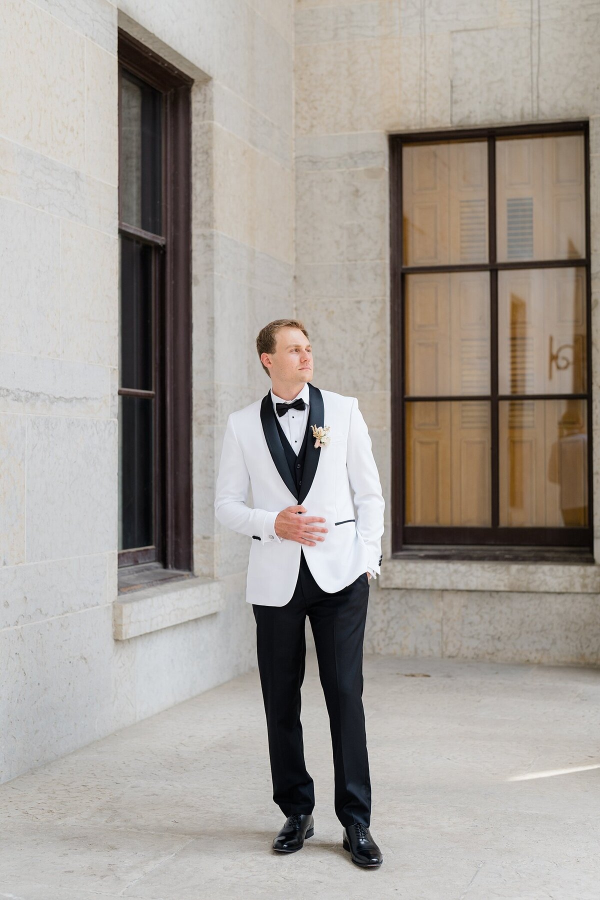 groom in a white and black tux posing at the Westin