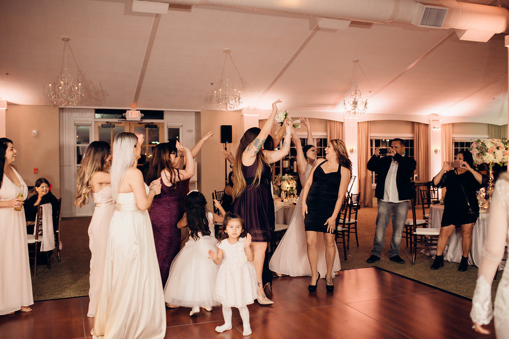 Wedding Photograph Of Women In White, Black, And Maroon Dresses Raising Their Hands Los Angeles