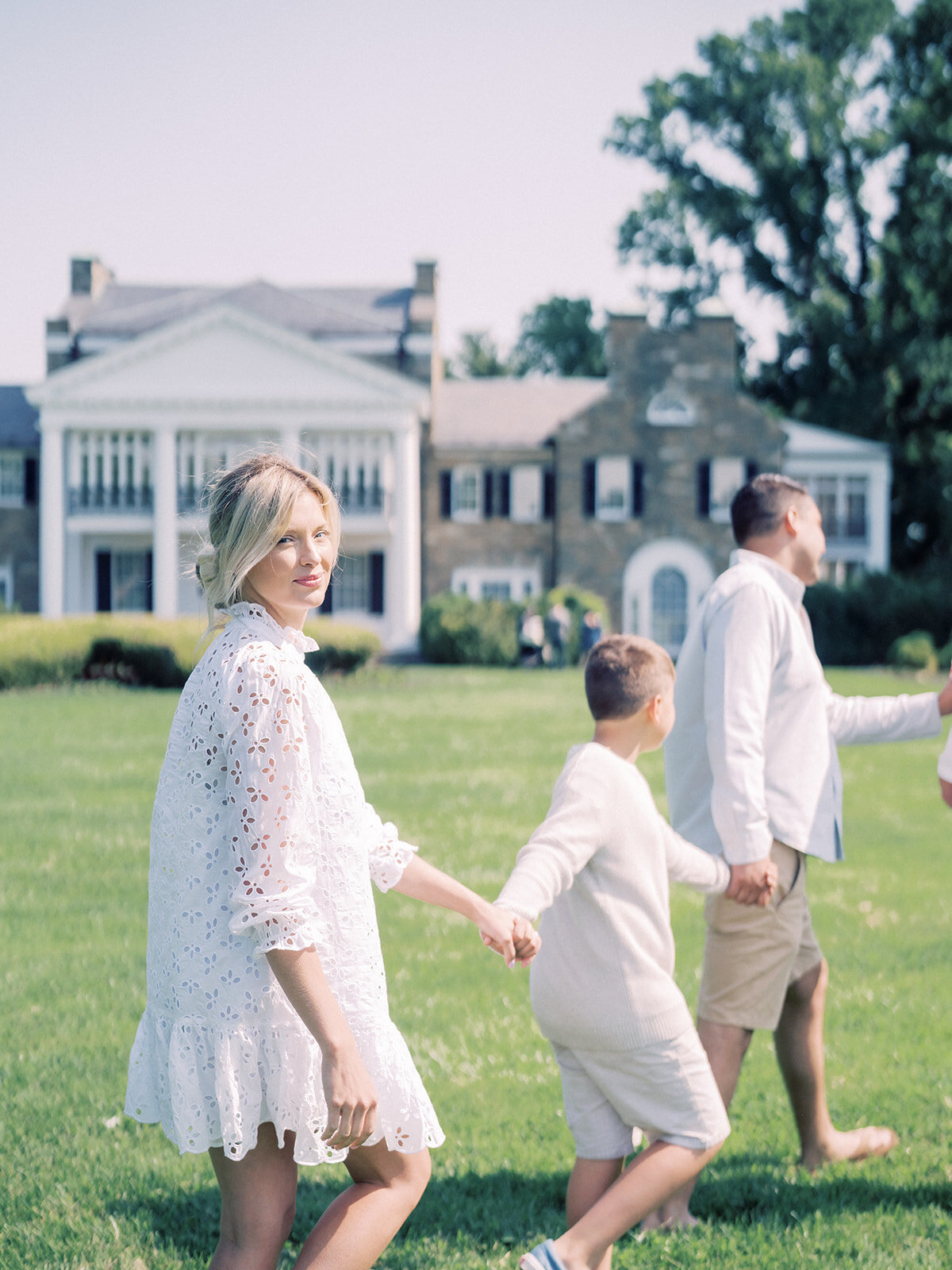 Blonde mother walks hand-in-hand with her family in front of Glen View Mansion in Rockville.