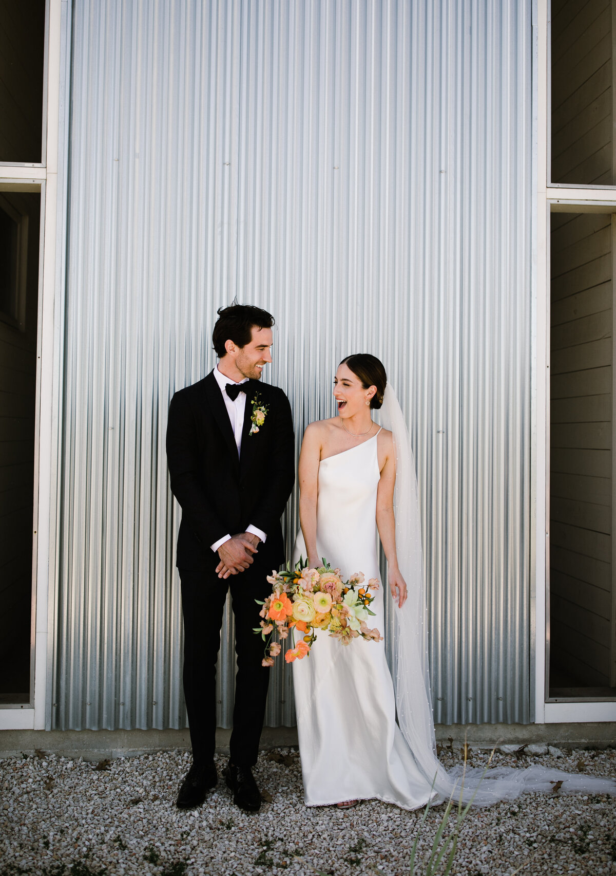 Bride and groom outside Prospect house, holding yellow and orange florals