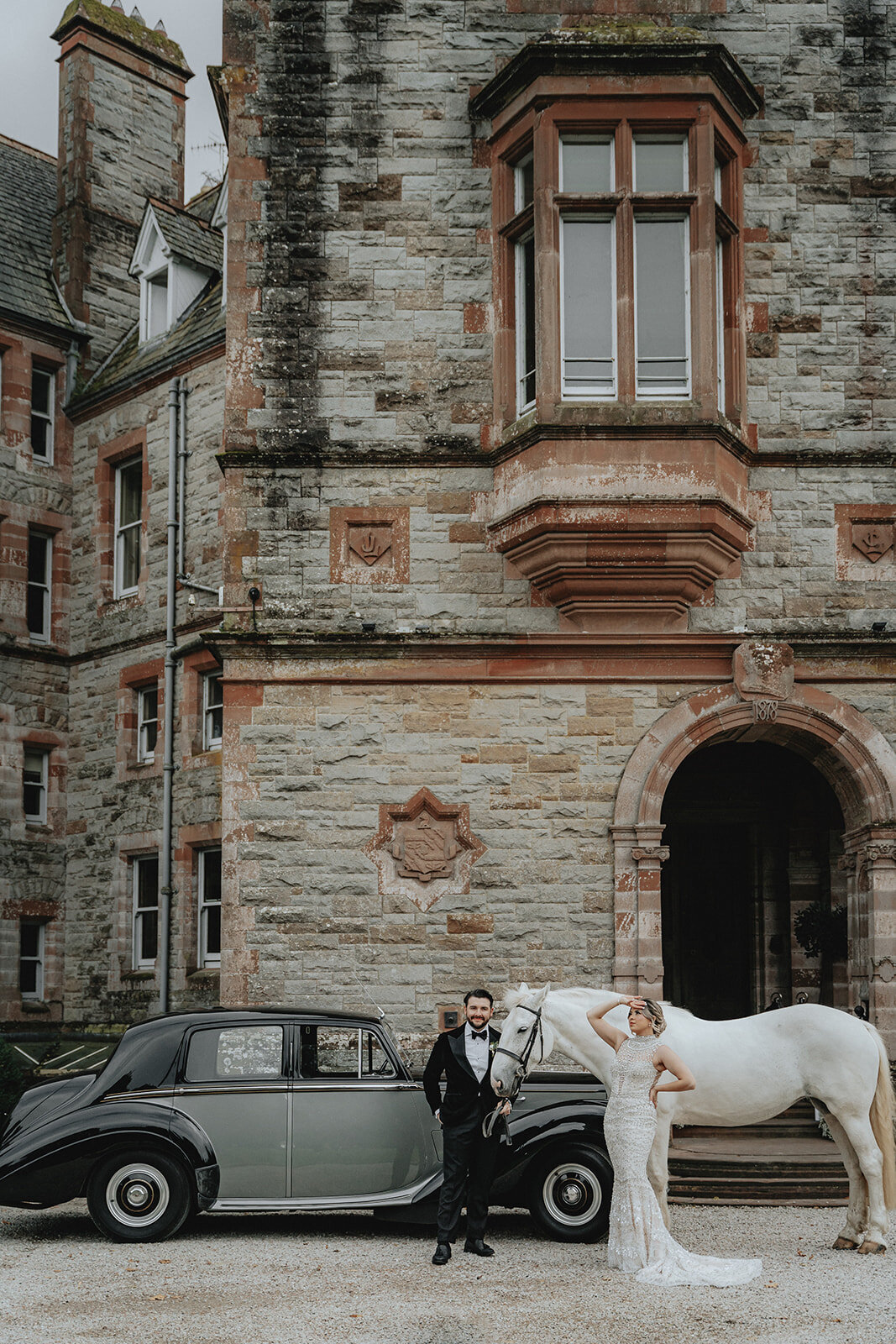 Bride and groom posing with horse and car in front of Ireland castle