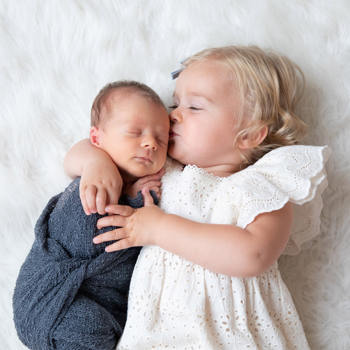 sibiling-kissing-newborn-on-head