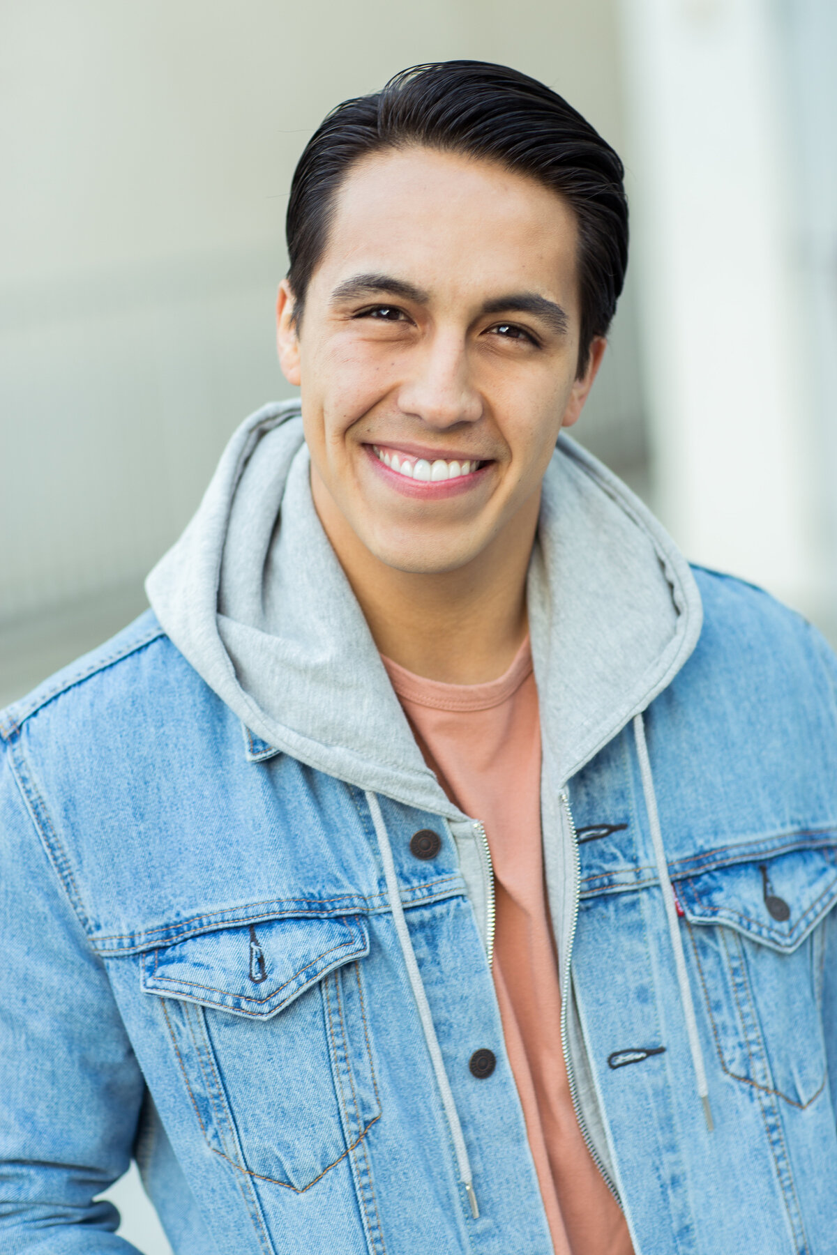 Headshot Photograph Of Young Man In Outer Light Blue Denim Hoodie And Inner Orange Shirt Los Angeles