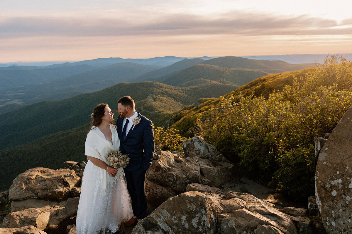 A bride and groom standing in front of the Blue Ridge Mountains on their elopement day in Virginia;