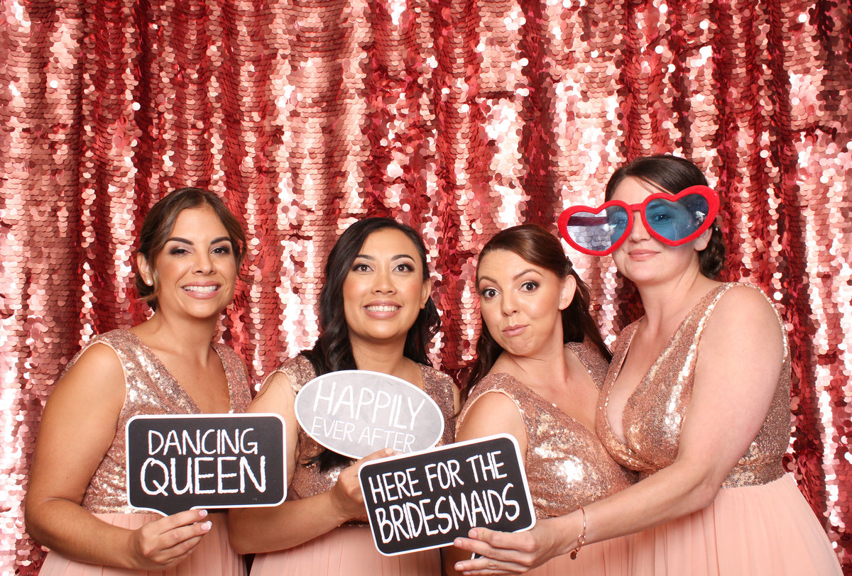Bridesmaids pose together in a photo booth at the wedding reception