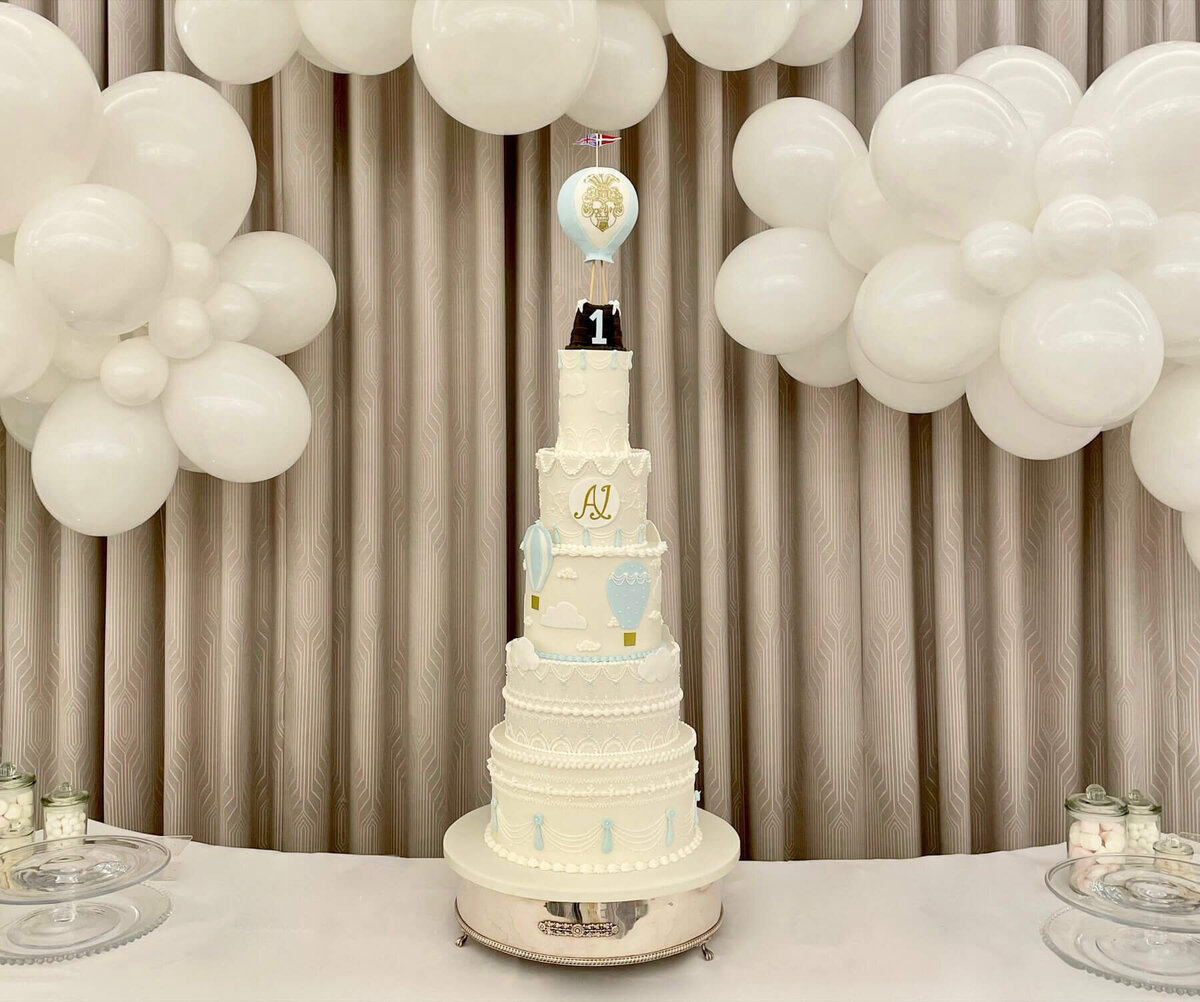 An elegant 5 tier birthday cake with a hot air balloon theme, including a hot air balloon at the top with a number 1