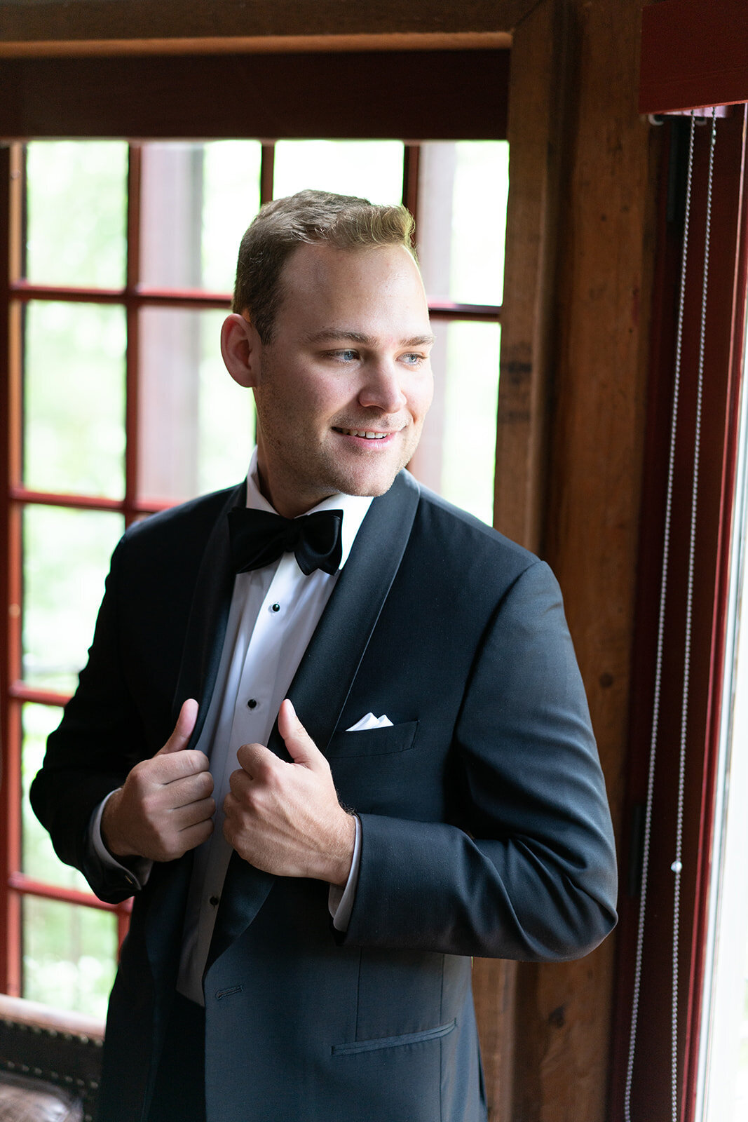 groom smiling while holding his tuxedo jacket