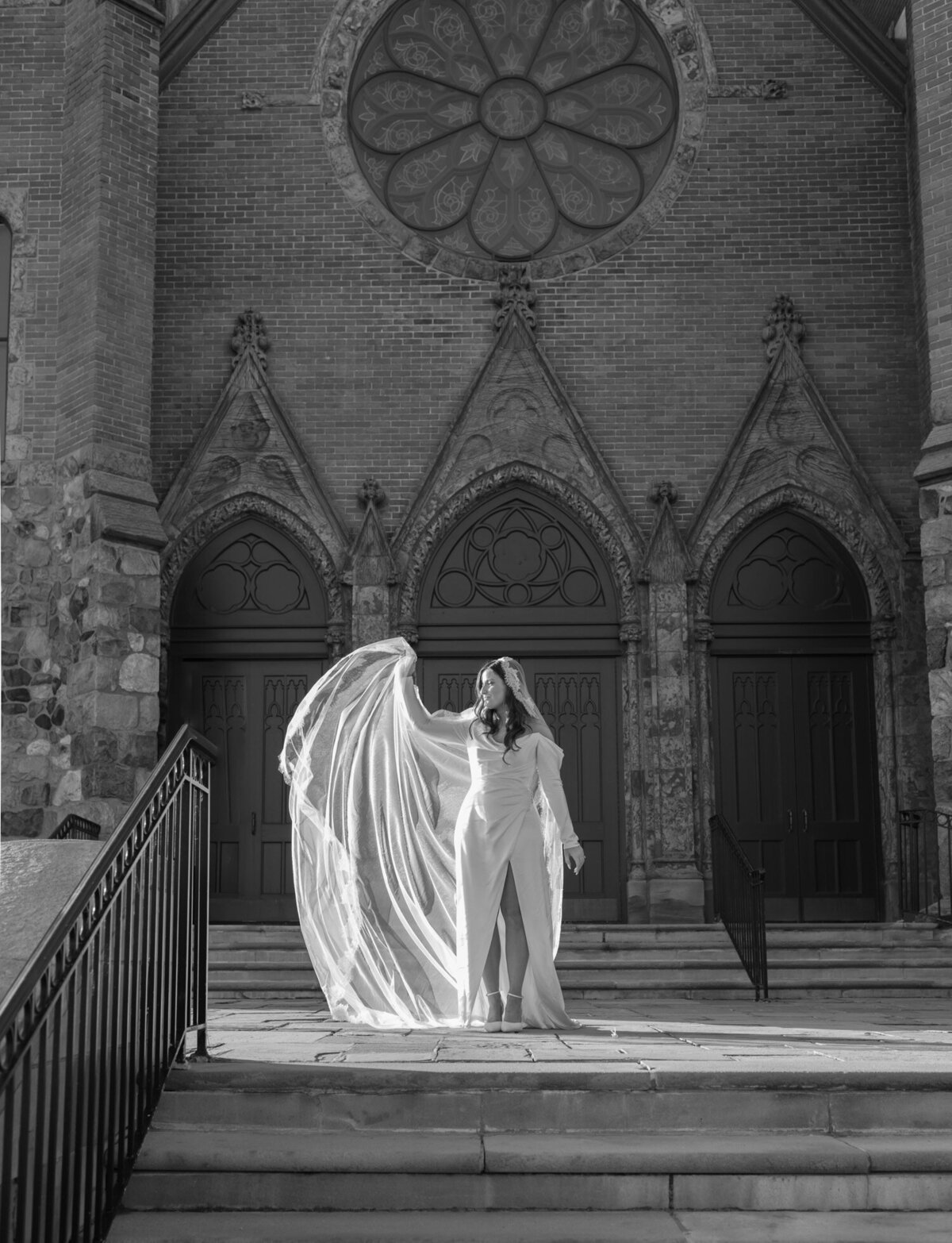 bride adjusts long lace cathedral veil at ornate historic cathedral in Detroit, Michigan