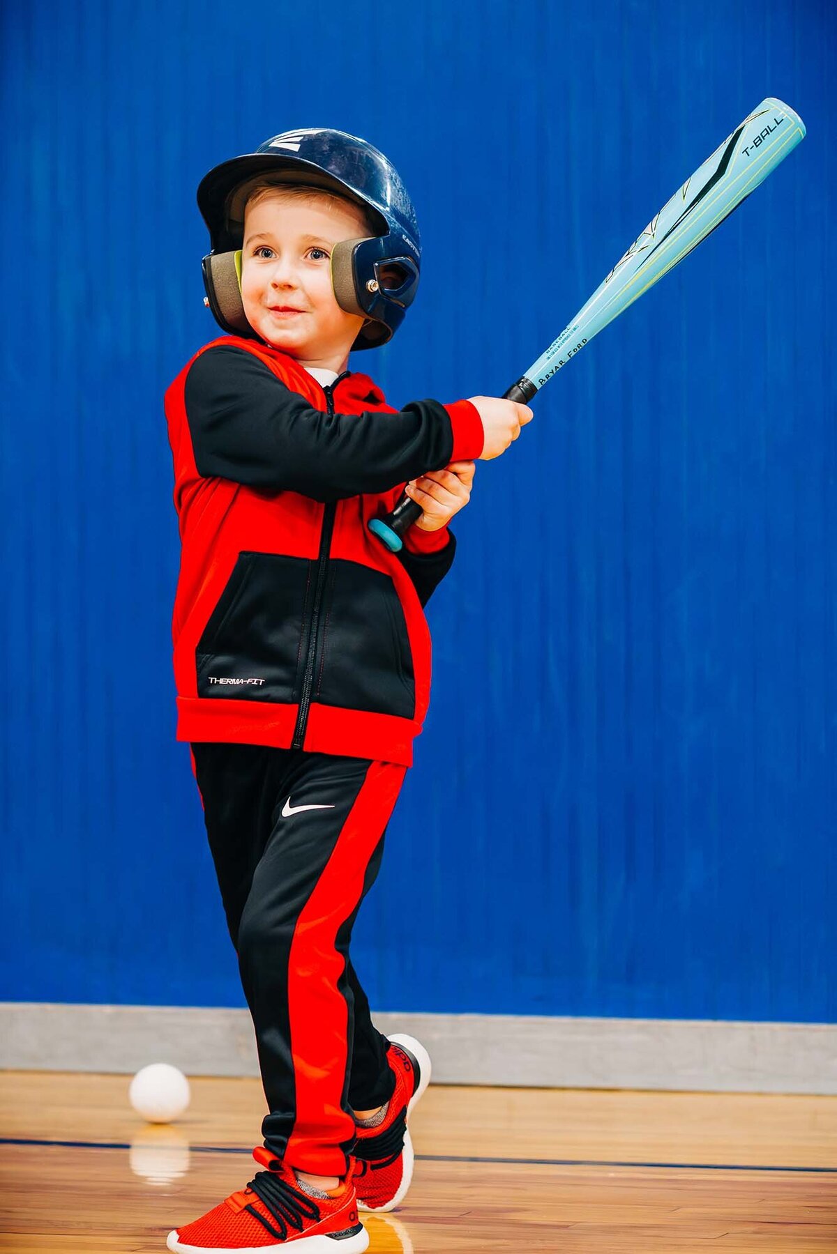 Little boy swinging bat at tee ball practice