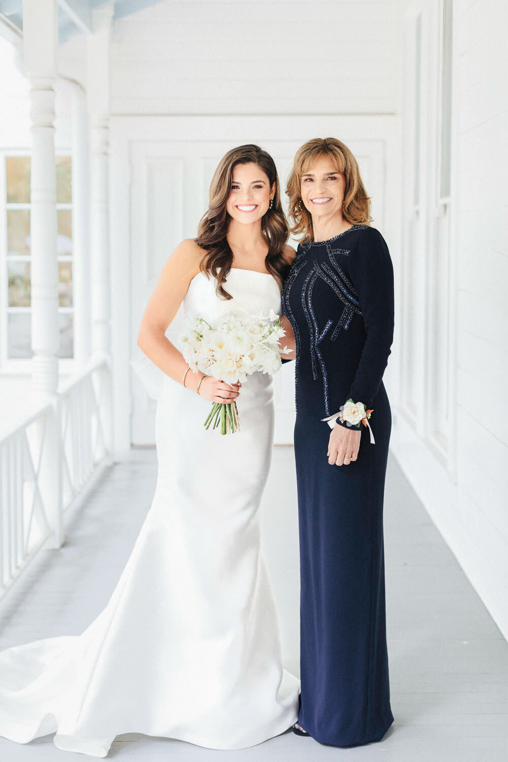 bride and mother in white wedding dress and blue gown posing for photo