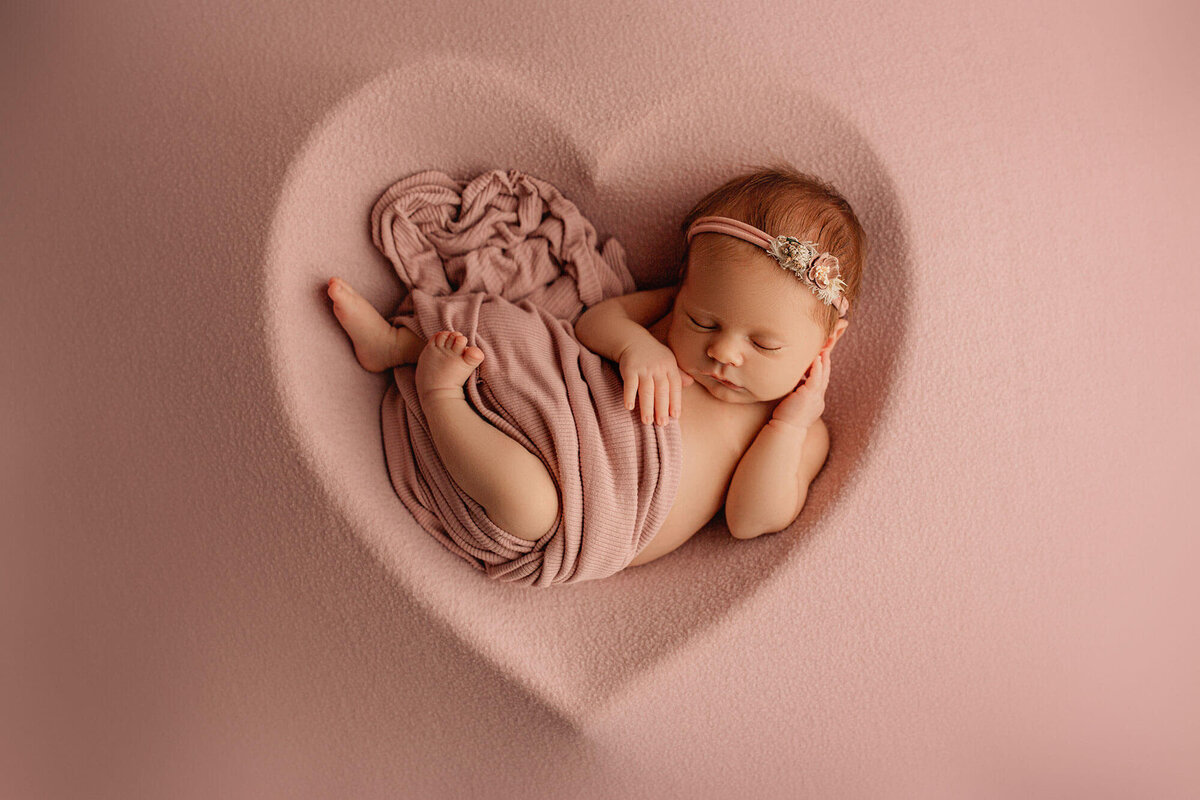 hamilton newborn photographer captures newborn baby sleeping in pink heart shaped bowl