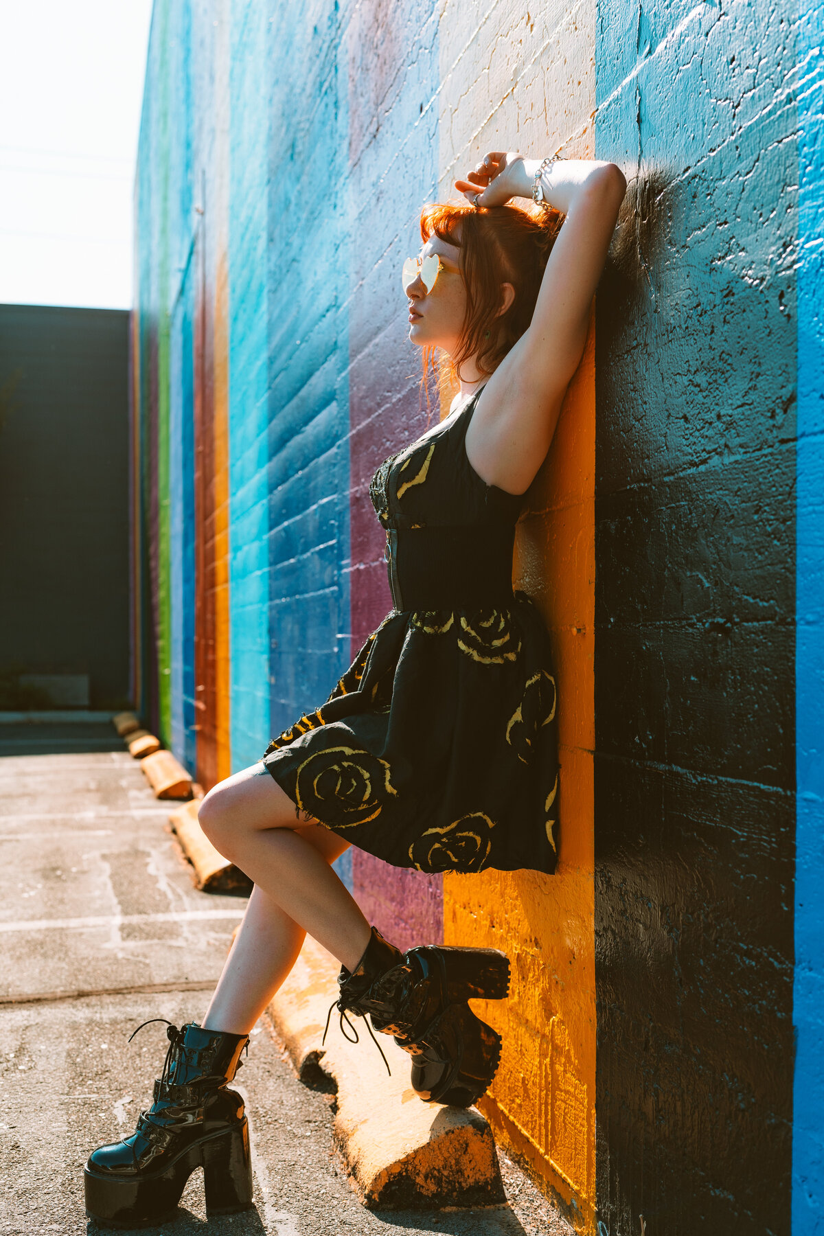 Woman in black dress leaning confidently against mural-covered wall – branding for creatives by Mewphotovideo