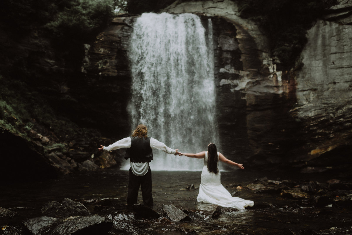 Bride and groom  with arms open at Looking Glass Falls in North Carolina
