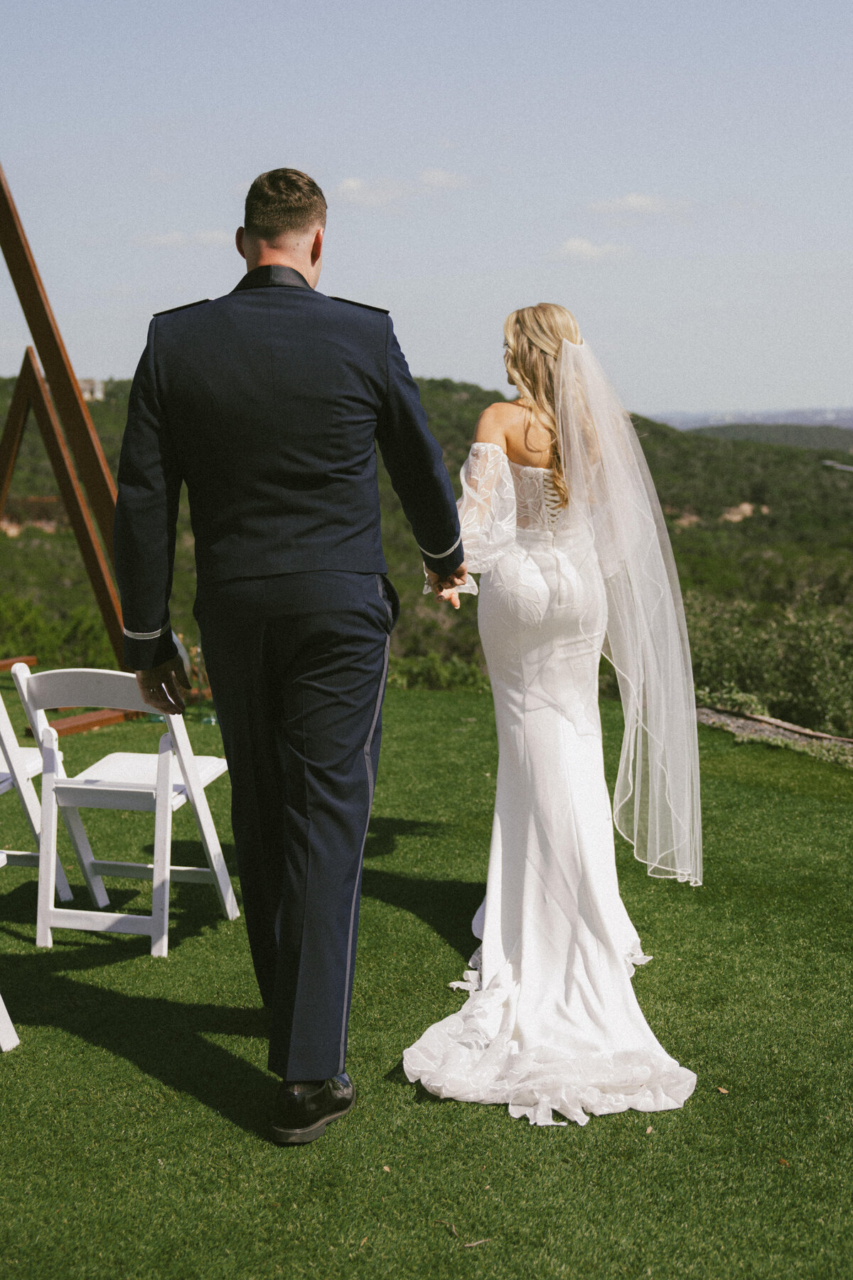 Bride leading groom while walking in the grass