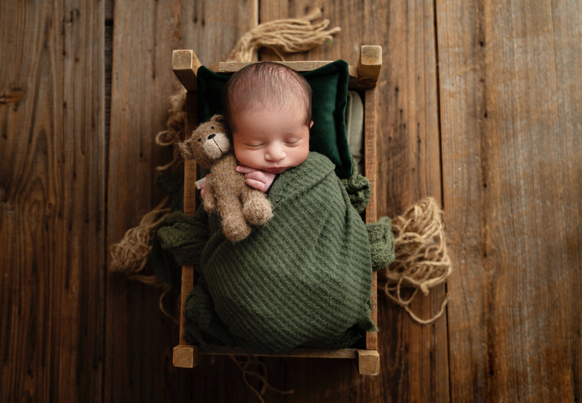 dallas newborn boy with bear on a bed