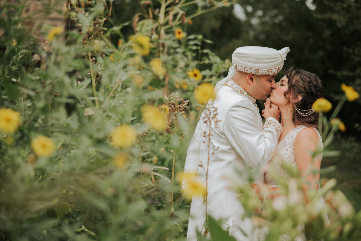 The bride and groom share an intimate moment embraced by the beautiful florals of Bartram's garden in Philadelphia.